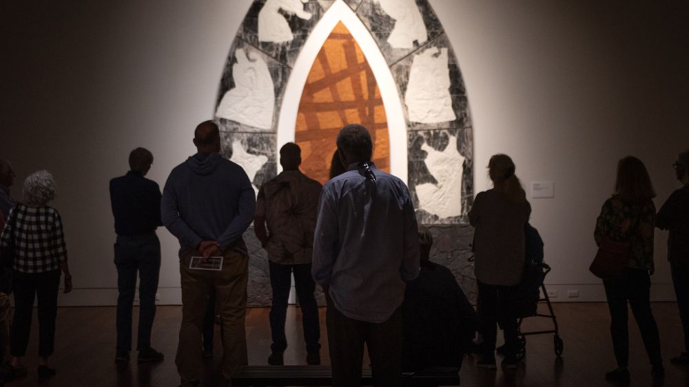 Group of people on museum tour viewing artwork.