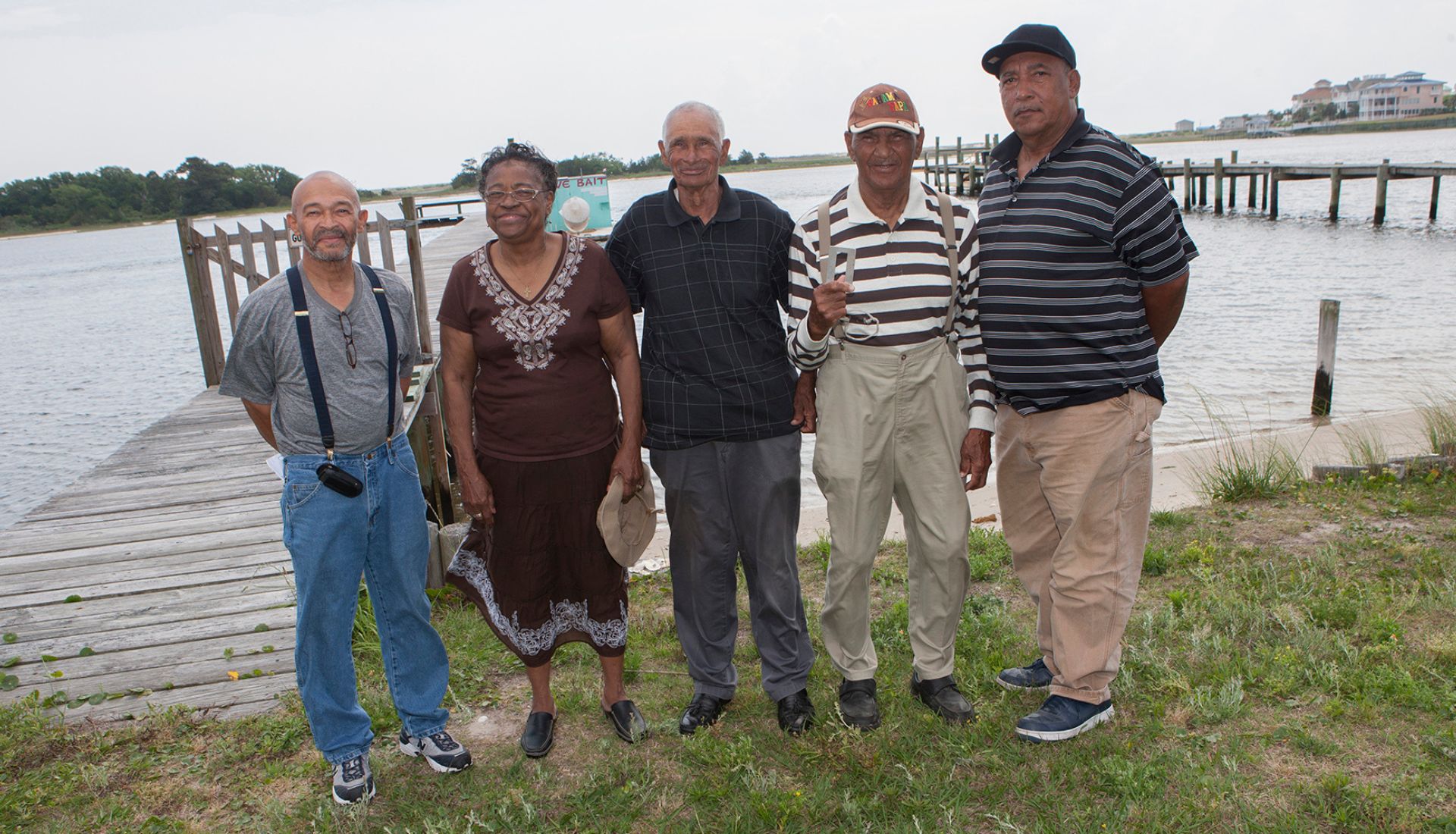Five individuals standing in front of a dock and body of water